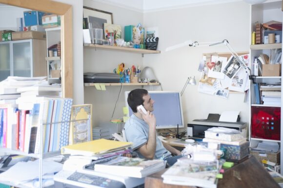 A man tries to work in his cluttered home office